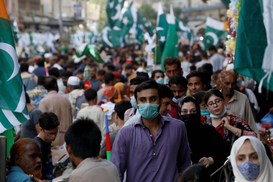 Young man wearing a mask in a crowded Karachi market during the H1N1 flu outbreak, while some people wear masks and others do not.