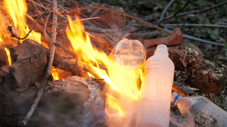 Burning plastic bottles in an open fire, releasing toxic fumes into the environment.