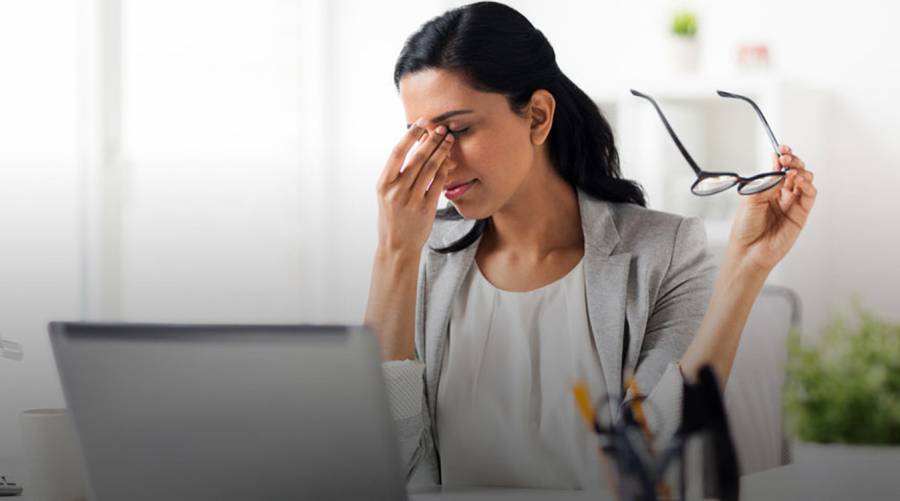 A young woman suffering from eye strain while using her laptop.